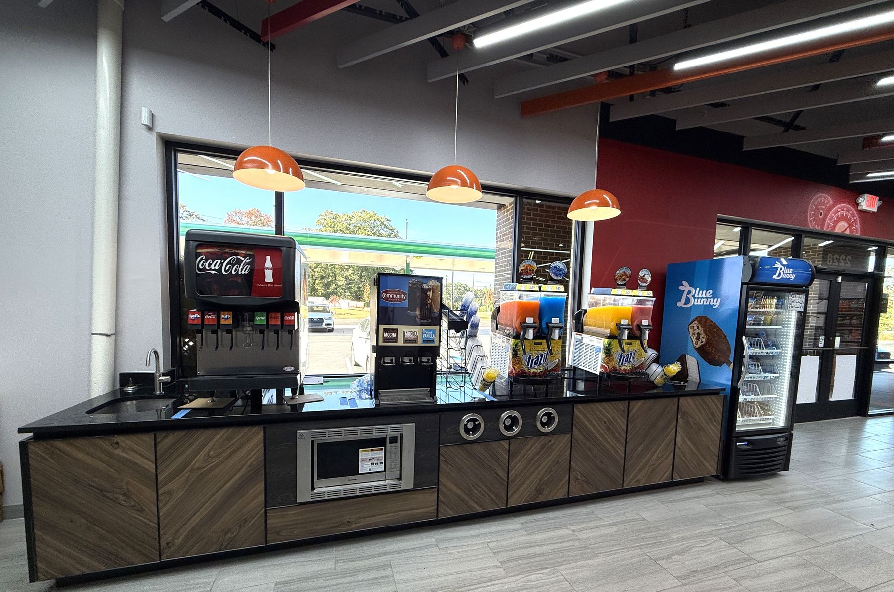 The fountain counter by the window with a Coca-Cola dispenser and orange pendant lights